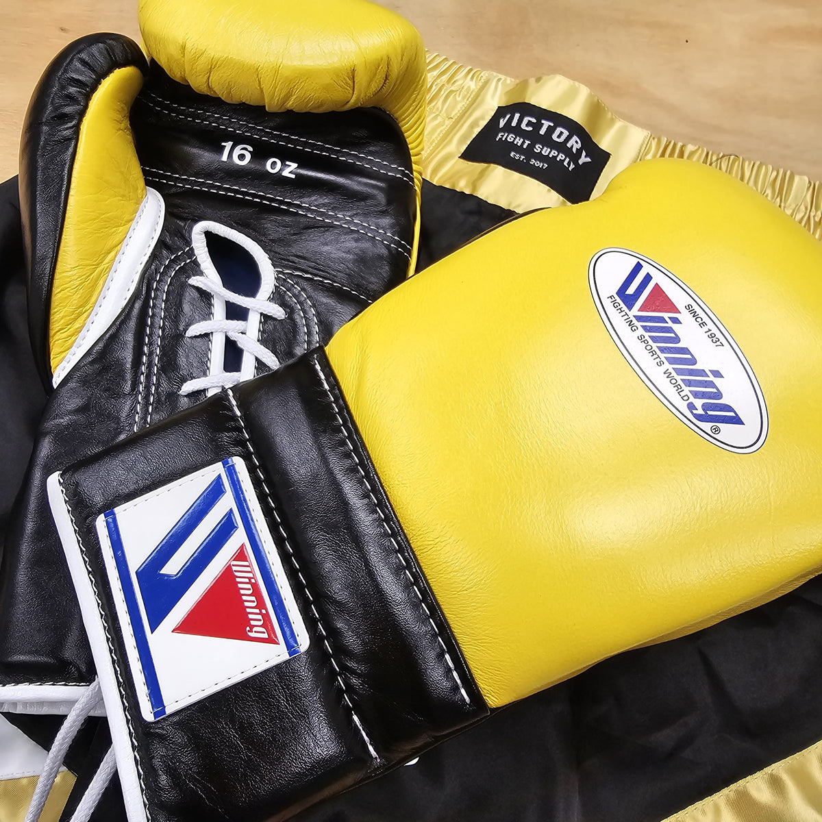 Pair of black and yellow boxing gloves with visible brand logos on a wooden surface.