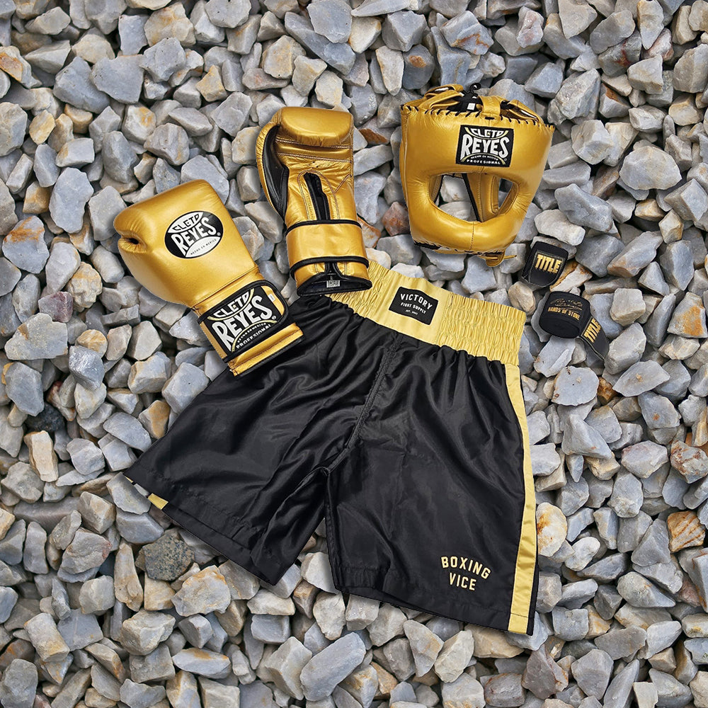 Boxing gloves and shorts on a rocky surface with 'Victory' branding.