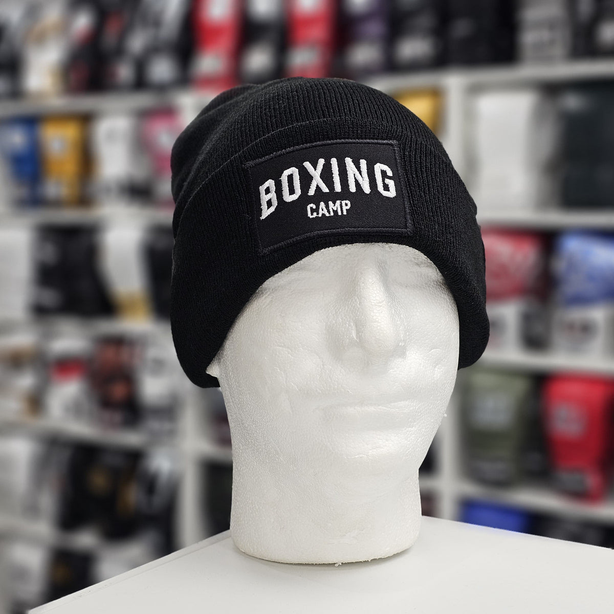 Black beanie with 'BOXING CAMP' patch on a mannequin head in a store setting.
