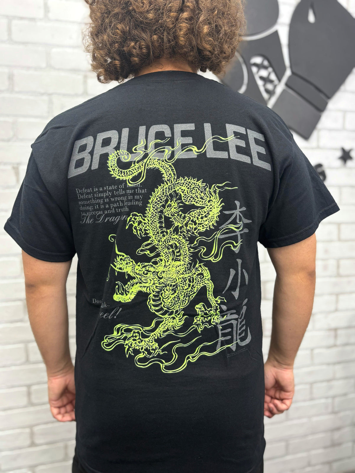 Person wearing a black t-shirt with a green dragon design and 'Bruce Lee' text on the back.