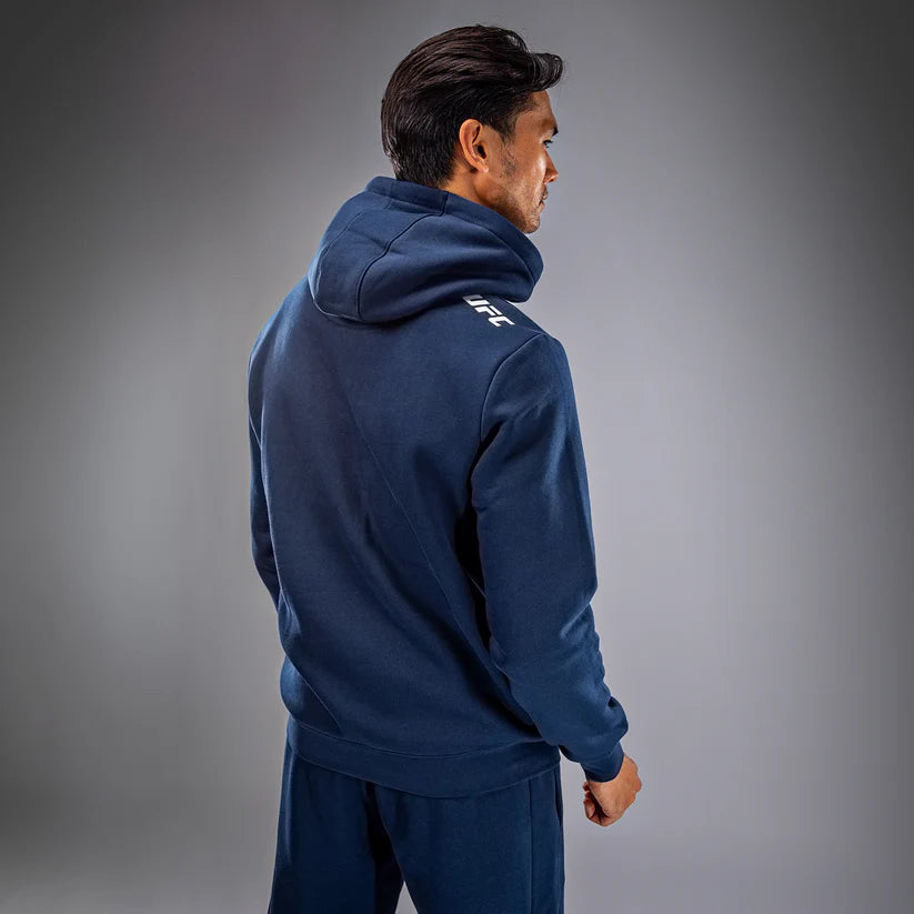 Person wearing a navy blue hoodie with UFC logo on a gray background