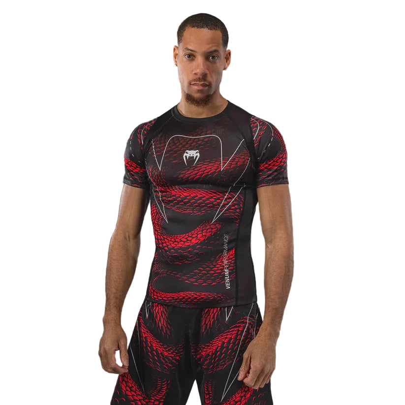 Person wearing a black and red compression outfit with a logo on a gray background