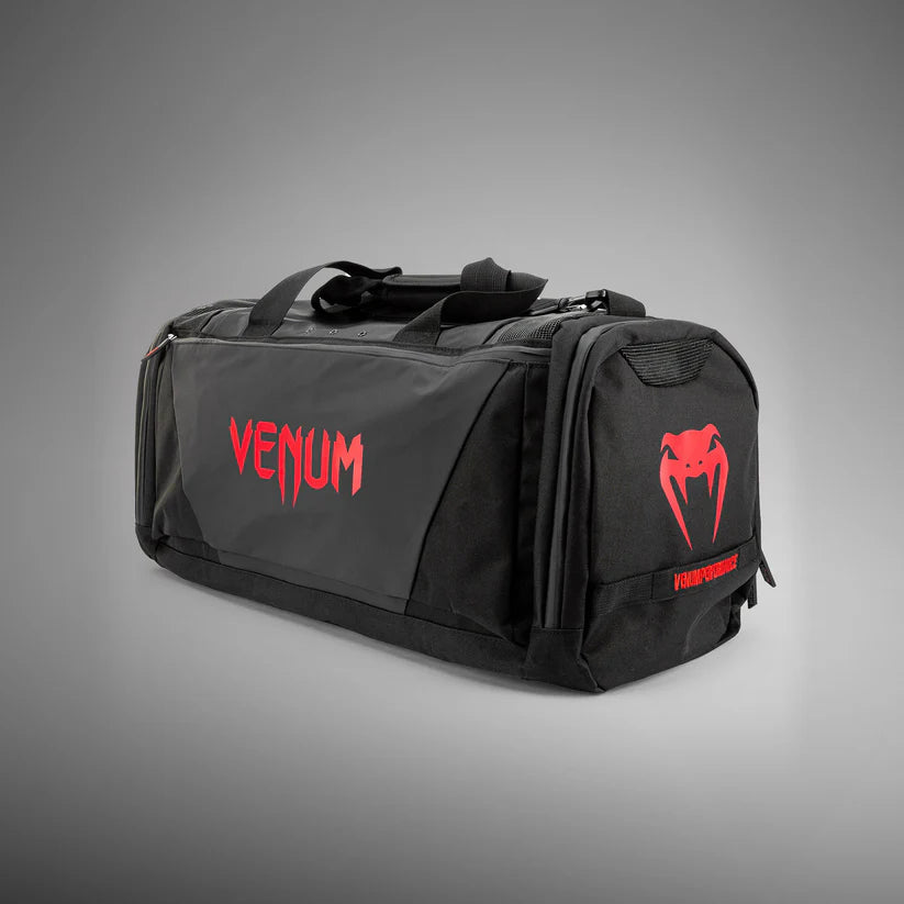 Black duffel bag with red 'Venum' logo on a gray background