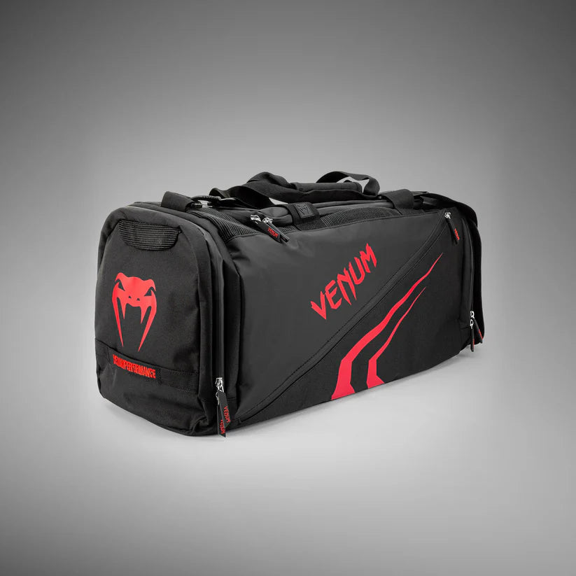 Black duffel bag with red Venum logo on a gray background