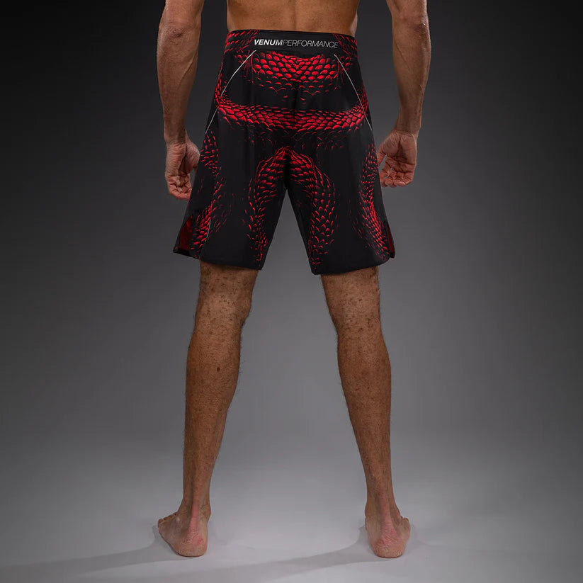 Person wearing black and red Venum performance shorts on a gray background
