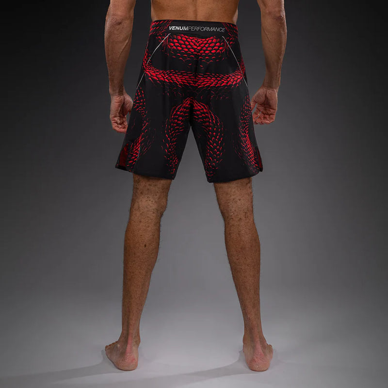Person wearing black and red Venum performance shorts on a gray background