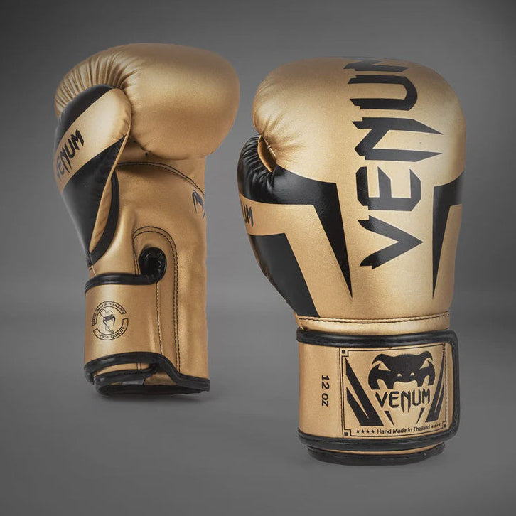 Pair of gold and black Venum boxing gloves on a gray background