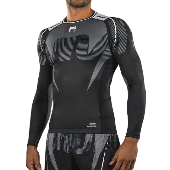 Man wearing a black compression outfit with a logo on a gray background