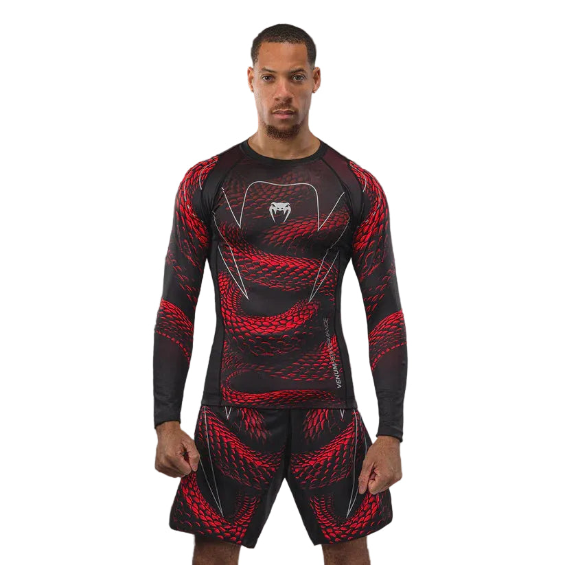 Person wearing a black and red athletic outfit with a logo on a dark background
