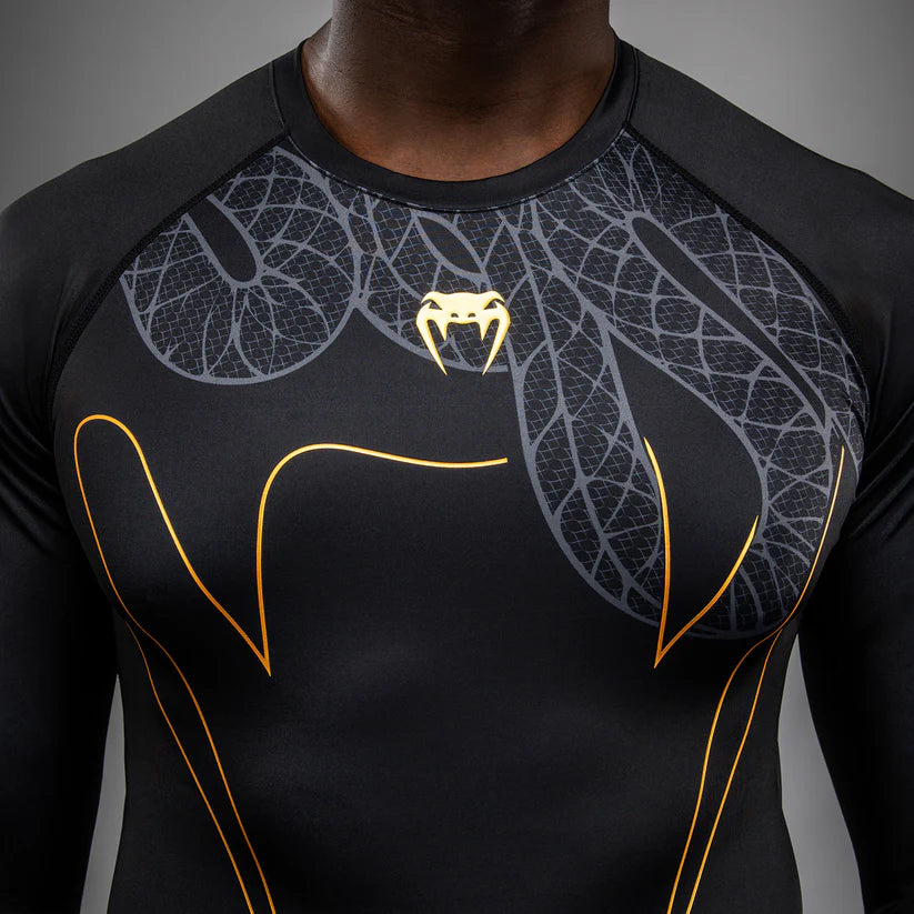 Black athletic shirt with gold and white designs on a gray background