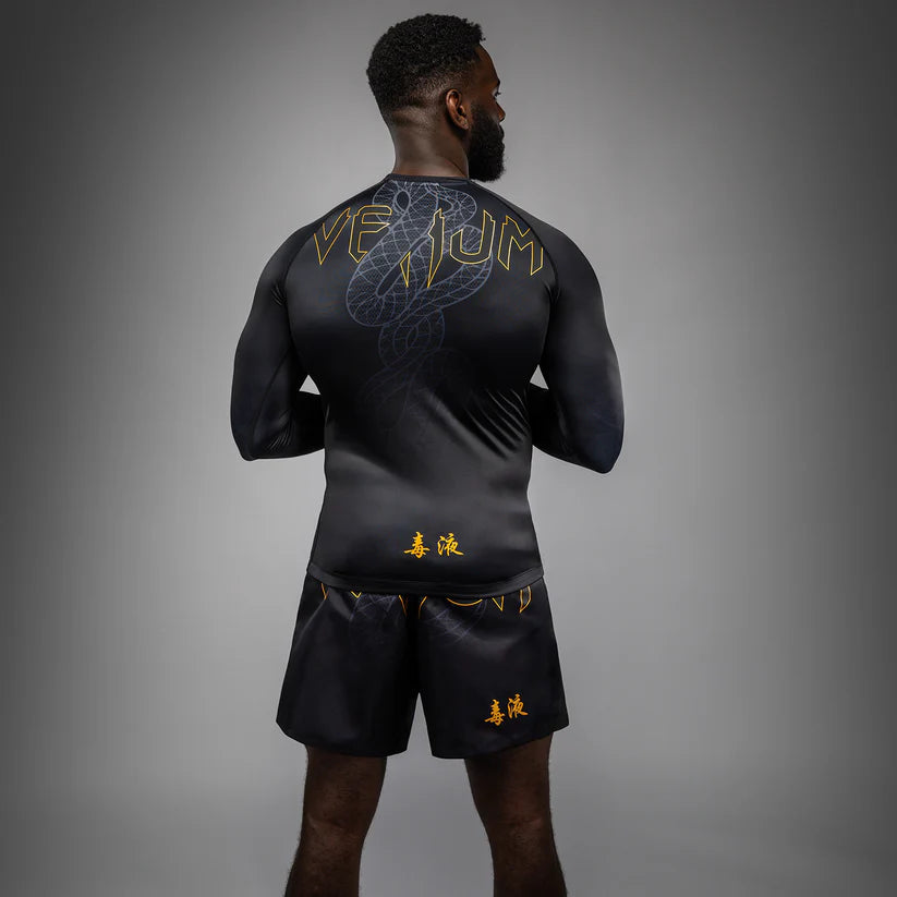 Person wearing a black athletic outfit with gold logos on a gray background