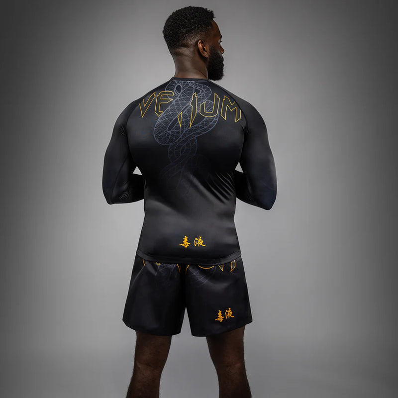 Person wearing a black athletic outfit with gold logos on a gray background