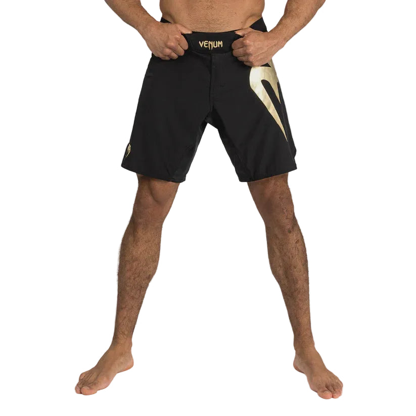 Person wearing black Venum shorts on a gray background