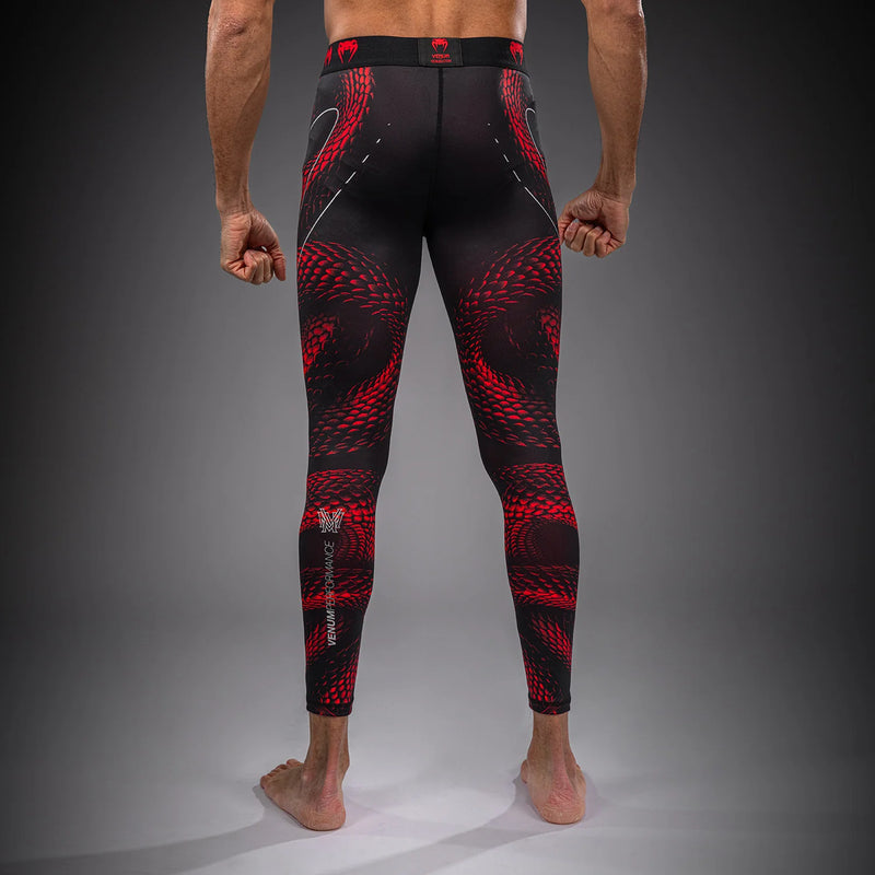 Person wearing black and red patterned leggings on a gray background
