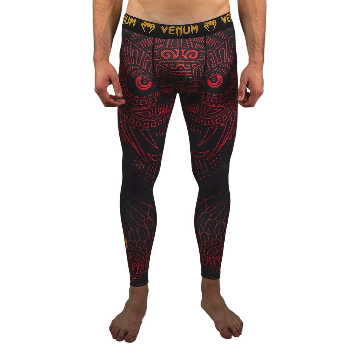 Person wearing black and red patterned Venum leggings on a gray background