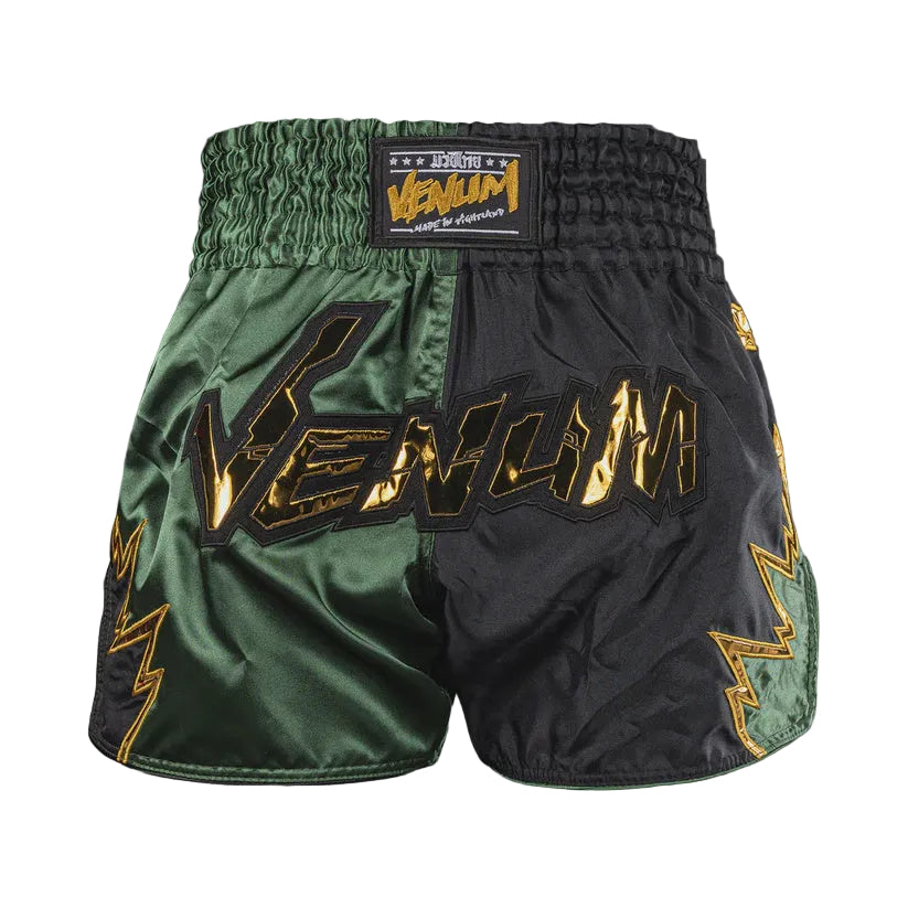 Green and black Venum boxing shorts on a gray background