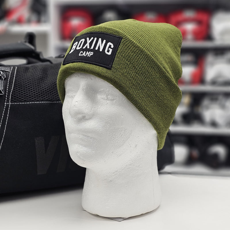 Green beanie with 'Boxing Camp' patch on a mannequin head against a blurred background.