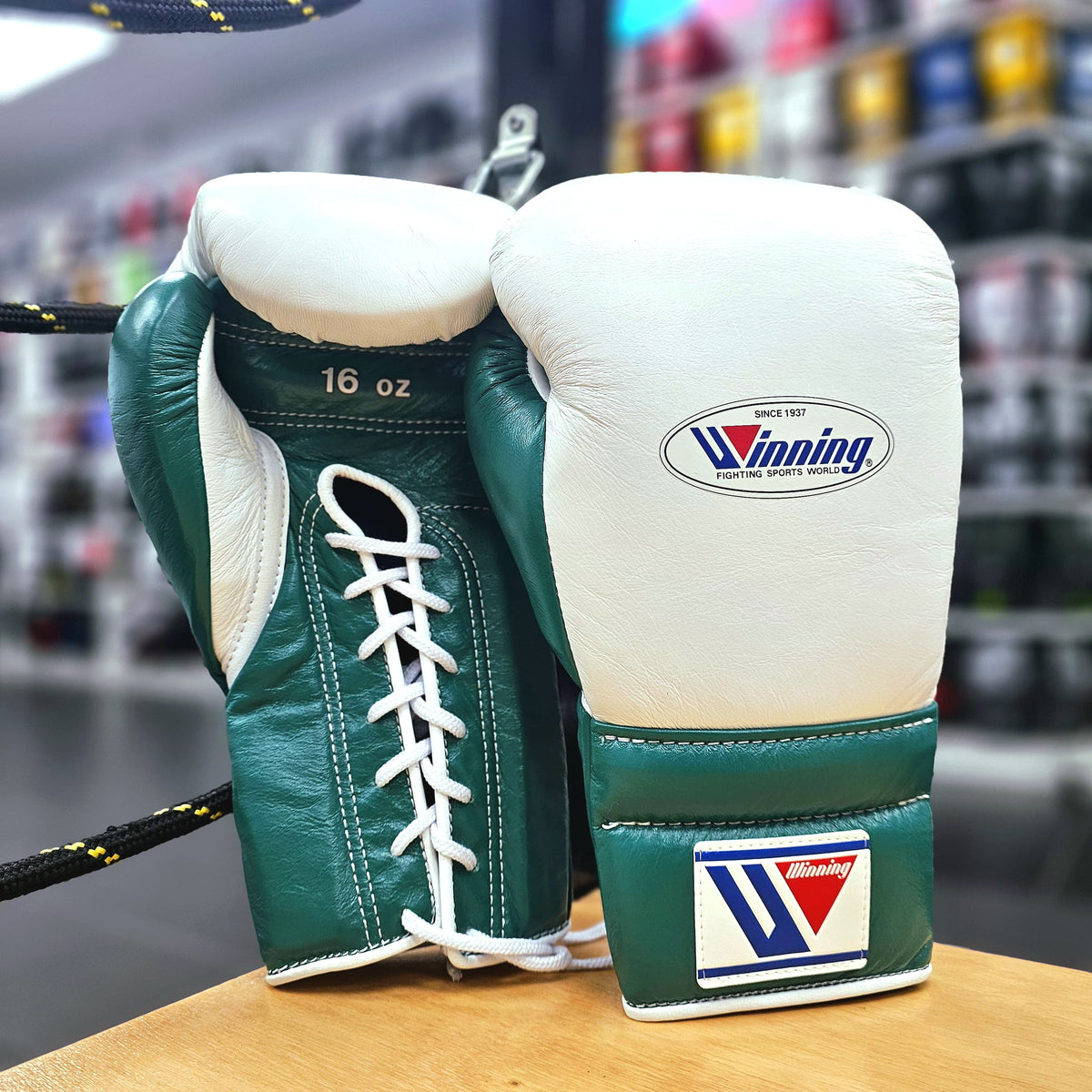 Green and white boxing gloves with 'Winning' logo on a wooden surface.