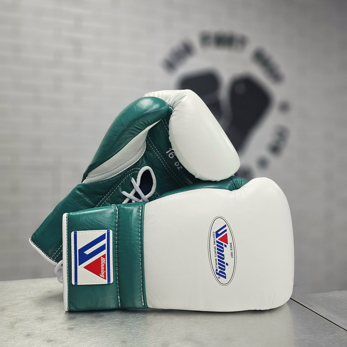 Winning Mint Green and white boxing gloves with a brand logo on a gray surface.