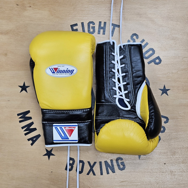 Pair of yellow and black boxing gloves on a wooden surface with 'Winning' branding.