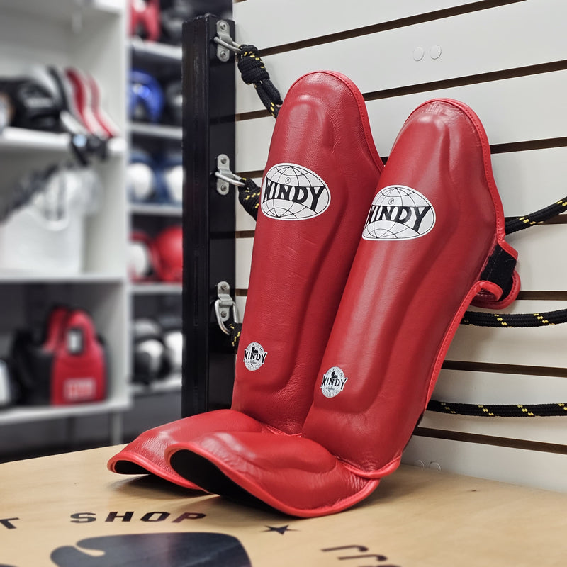 Red shin guards with 'Lindy' branding on a wooden surface.