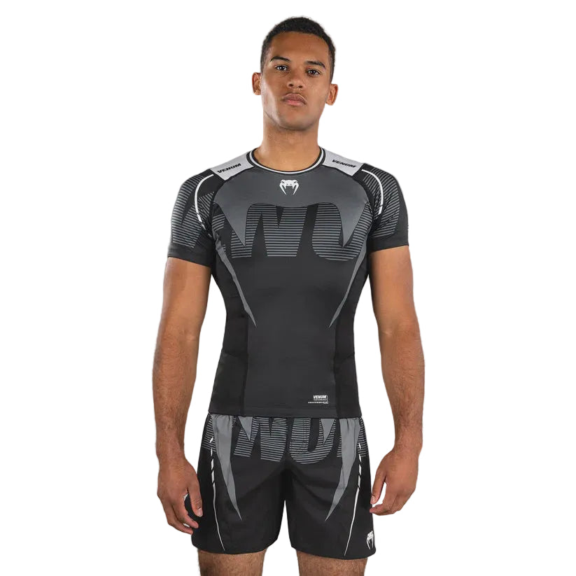 Person wearing a black athletic outfit with a brand logo on a gray background